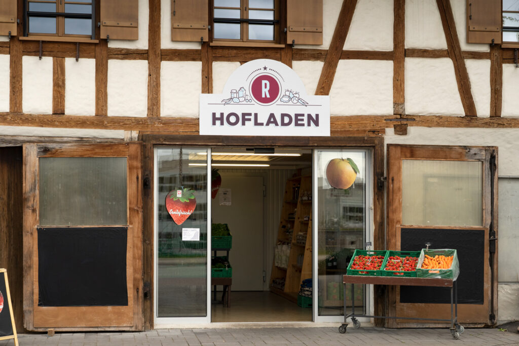 Der Hofladen auf dem Rüschenhof in Zug mit geöffneter Eingangstüre und frischen Erdbeeren in der Auslage.